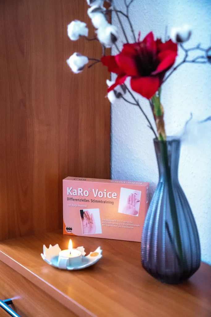 Das Chilax KaRo Voice Premium-Set ist neben einer Vase mit Blumen und einer Kerze auf einem Holzregal platziert.